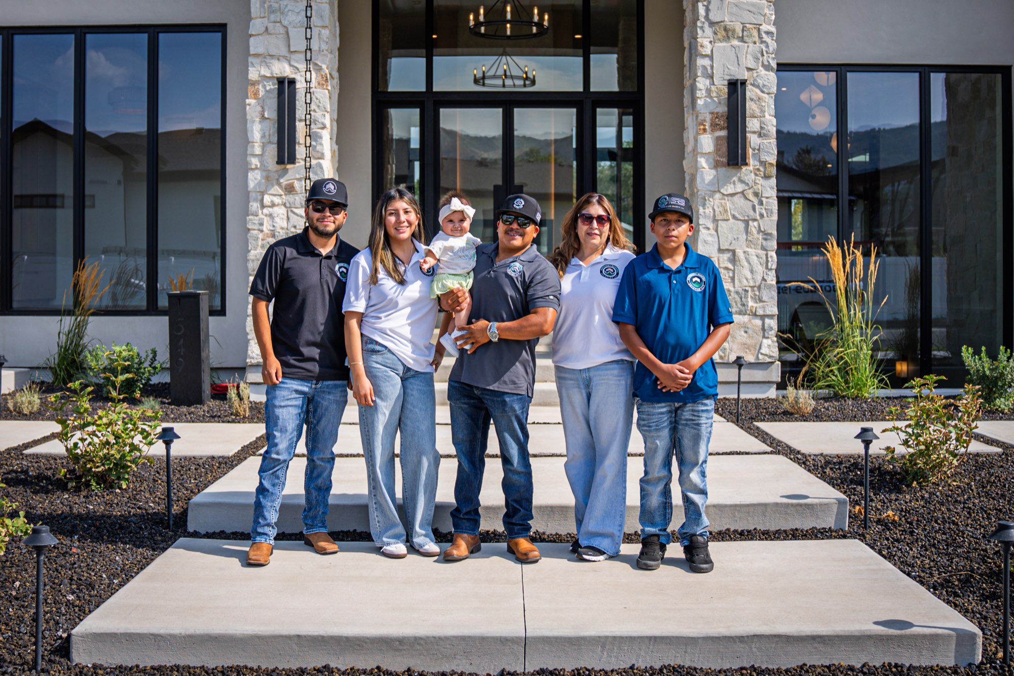 The Lopez family wearing Southern Roofing Solutions shirts outside a finished Utah home