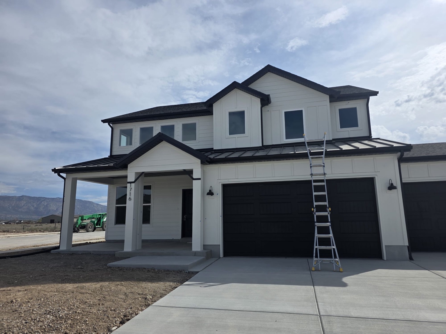New construction home with black gutters, fascia and metal accent roofing