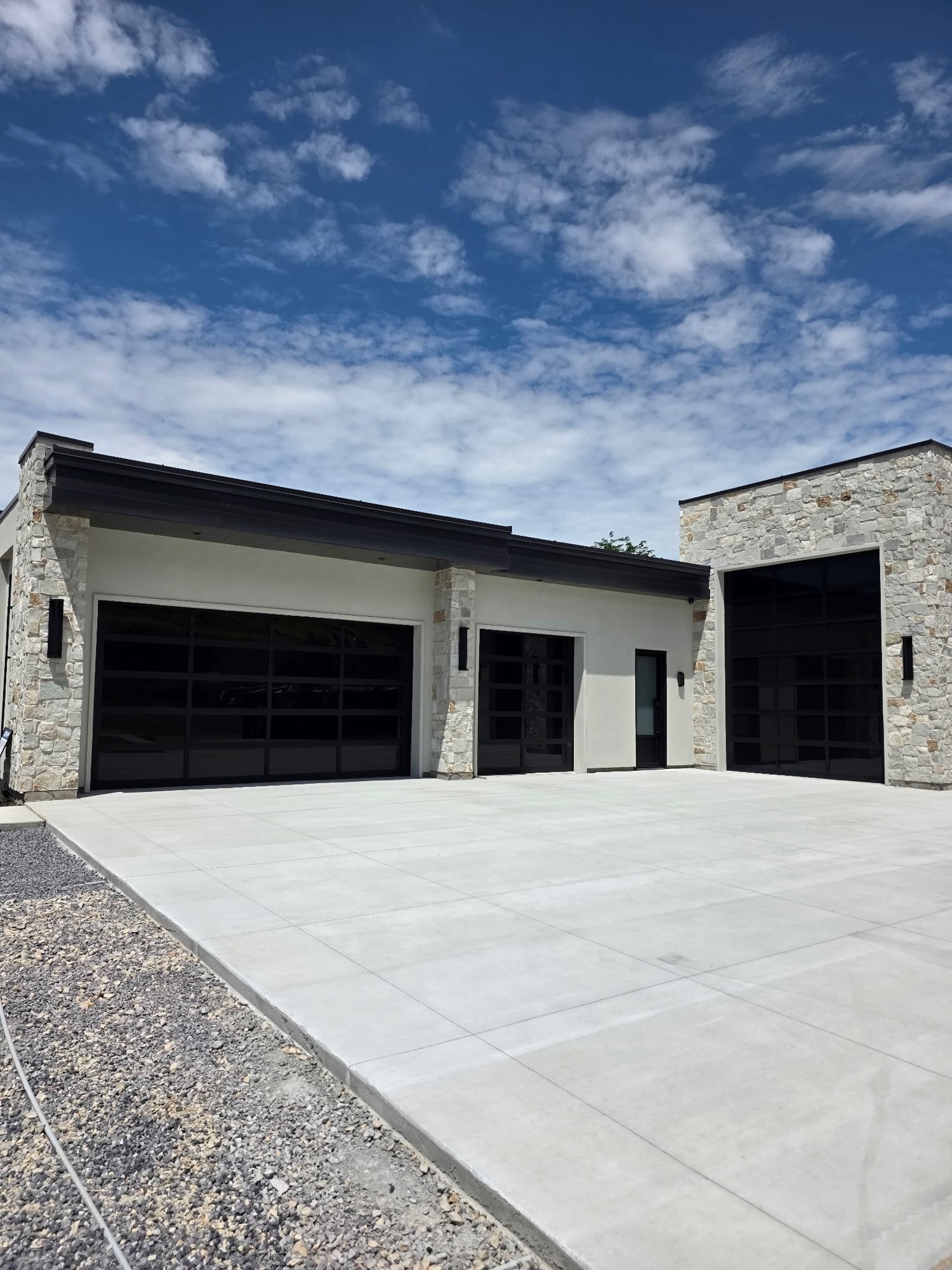 Modern stone and stucco garage with custom dark fascia and a flat roofline in Utah