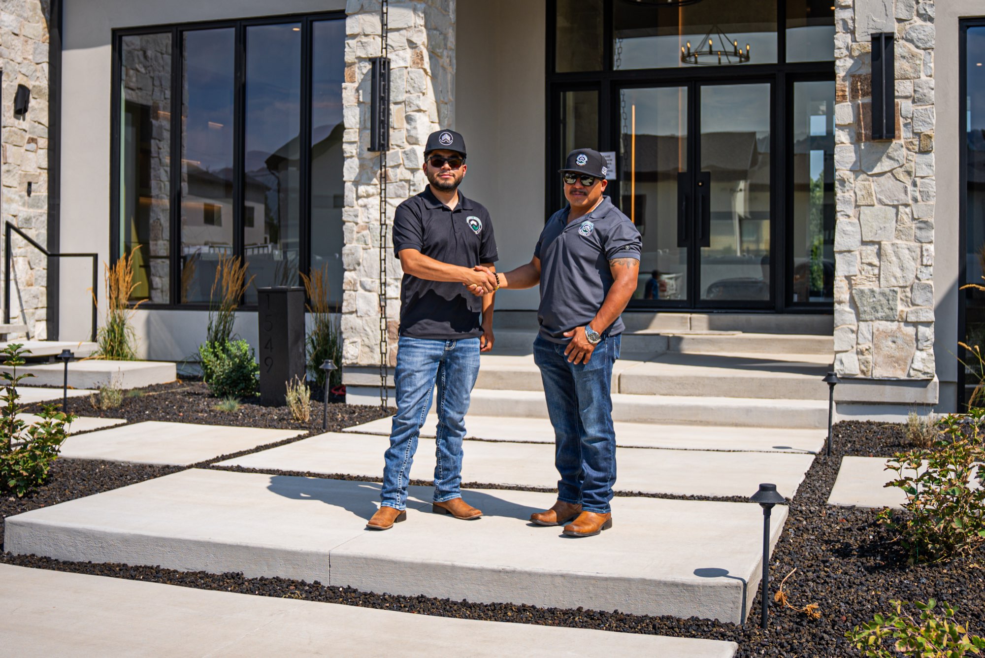 Southern Roofing Solutions owners Juan and Alex Lopez shaking hands outside a completed modern home in Utah