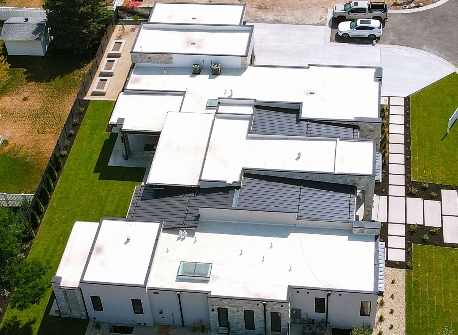 Overhead aerial view of a completed white membrane flat roof with dark metal accent sections on a modern Utah home