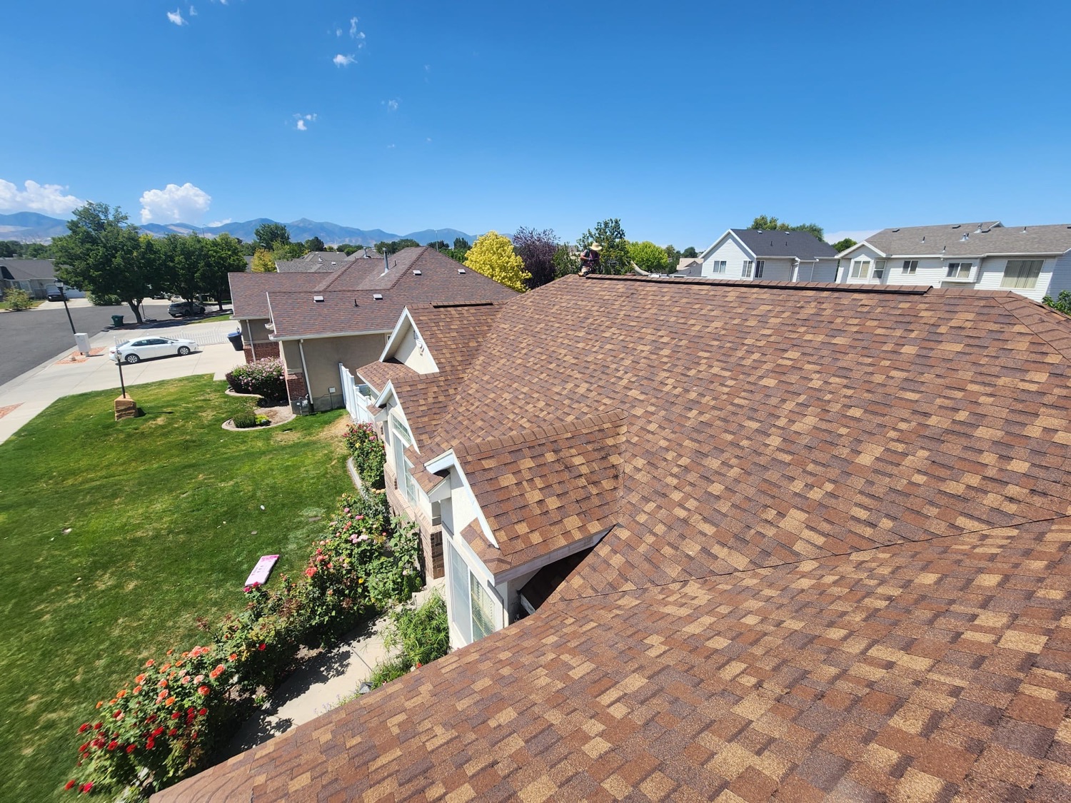Completed asphalt shingle roof on a Salt Lake Valley home with the Wasatch mountains behind it
