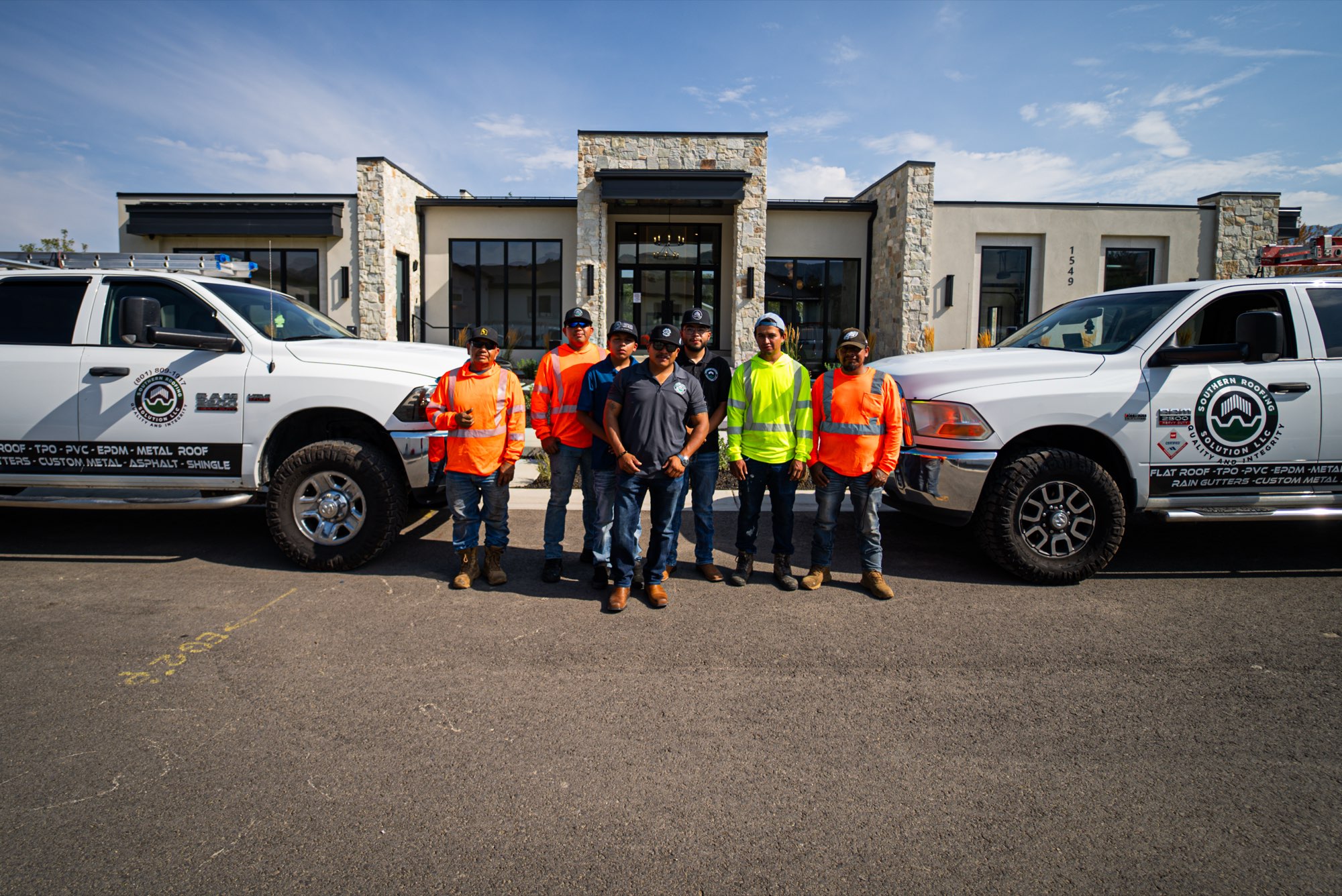 The Southern Roofing Solutions crew standing together between two company trucks outside a completed Utah home
